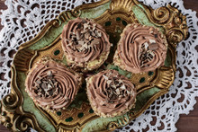 Biscuit Cakes Sprinkled With Nut Crumb And Decorated With Chocolate Cream Are On A Vintage Wooden Tray On A White Lace Doily, Top View