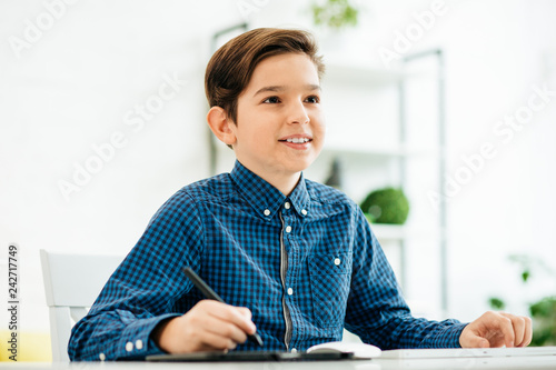Fotografie, Obraz Progressive schoolboy smiling while using modern gadgets