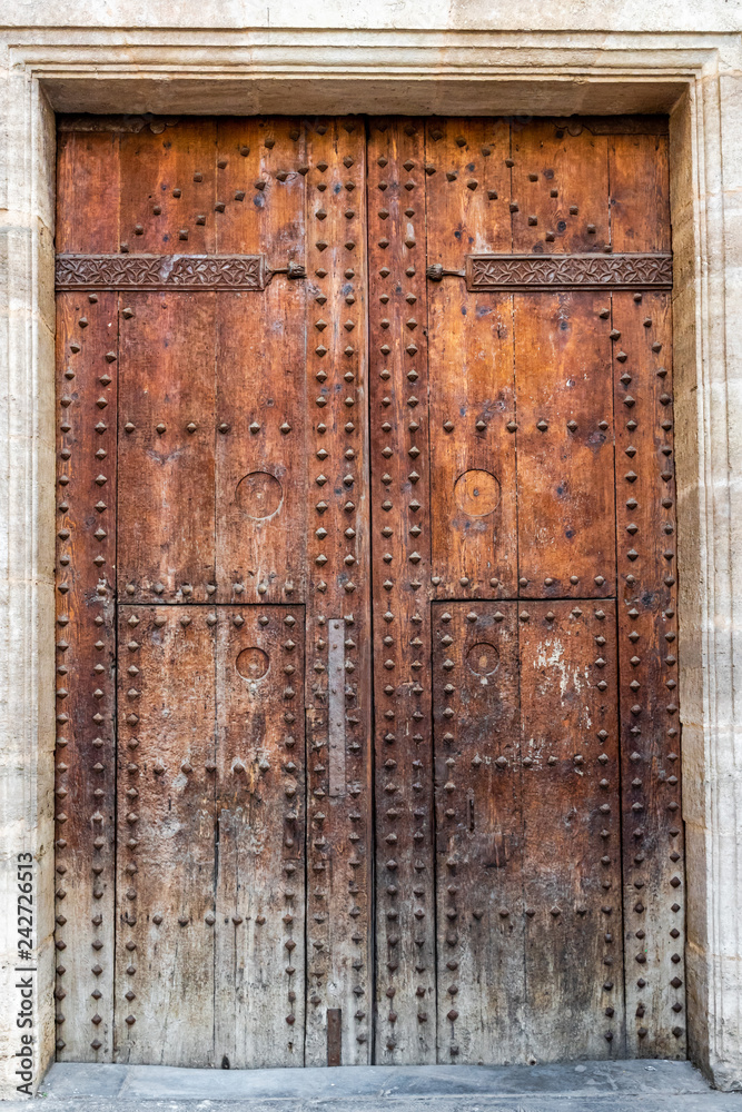 Medieval doors. Spanish traditional ornament on wooden gates. Old wooden gate texture. Strong fortress Spain. Stock Photo Adobe Stock