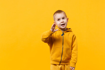 little cute kid boy 3-4 years old wearing yellow clothes isolated on bright orange wall background, 