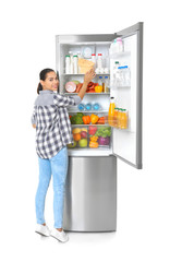 Wall Mural - Young woman near open refrigerator on white background