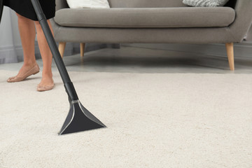 Wall Mural - Woman removing dirt from carpet with vacuum cleaner indoors, closeup. Space for text