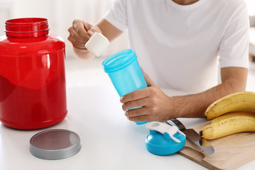 Poster - Young man preparing protein shake at table indoors, closeup