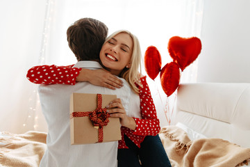 Wall Mural - Couple. Love. Valentine's day. Man and woman are hugging, she is holding a gift box and smiling