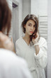© evgeniykleymenov - portrait of a beautiful woman in the bathroom. cheerful young girl looks at herself in the mirror, grimaces