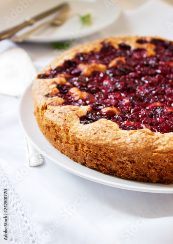 Valokuva Homemade cherry pie served with cream on a light background with cherry leaves and flowers