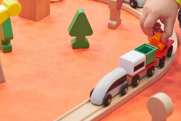 Wall Mural - Children playing with wooden train. Toy railroad. Toddler kid and baby play with blocks, trains and cars. Educational toys for preschool and kindergarten child. View from above, kids on the floor.