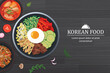 Bibimbap in the bowl on black wood table top view. Korea food background.