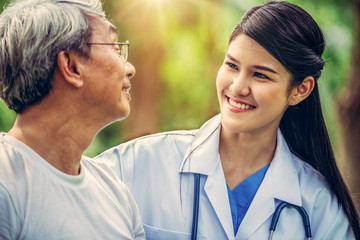 Wall Mural - Friendly doctor taking care of senior man in the hospital garden. Medical and healthcare doctor service concept.