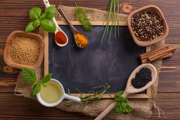 Mixed spices and herbs on wooden spoons with blackboard.