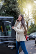 Attraktive Geschäftsfrau mit Handy in der Hand steigt in ein schwarzes Taxi in London