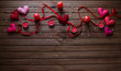 © Svitlana - Red, pink felted hearts on the red ribbon  with candles and heart shaped elements on the wooden background. Top arranged