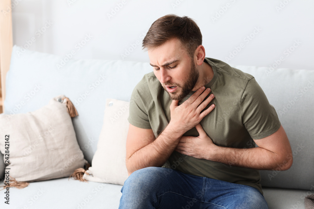 Young man having asthma attack at home - obrazy, fototapety, plakaty 