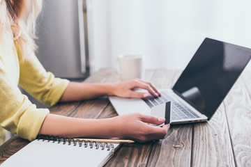 cropped view of woman holding credit card and using laptop