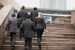 © Erickson Stock - Group of businesspeople walking up a flight of stairs outside a building in the city.