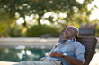 © Erickson Stock - Mid-adult man relaxing pool-side at sunset.