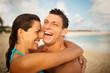 © Erickson Stock - Laughing mid-adult couple hugging on a sandy beach.