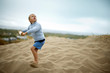© Erickson Stock - Boy holding kite reel while standing on sand dune