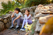 © Erickson Stock - Unhappy brother and sister sitting next to each other on a stone step.