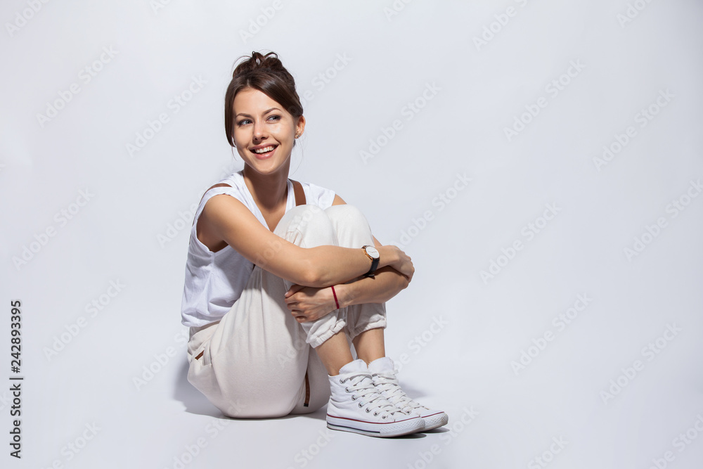 Portrait of a casual happy woman sitting on the floor on white ...