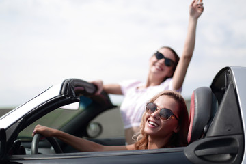 close up.two happy young women in a convertible car