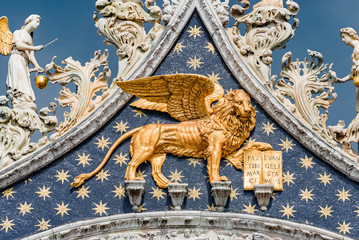 Wall Mural - golden winged lion with parchment as roof decoration of basilica san marco in venice, italy, summer 