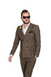 © _robbie_ - Cool trendy businessman in a brown suit, white shirt and sunglasses walking against a white background with a focused tough look.