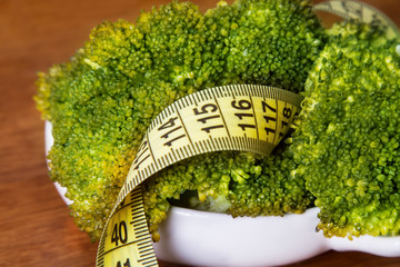 cooked green broccoli and metric tape, concept of diet and health