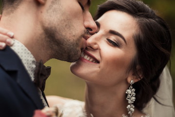 A very beautiful bride girl in a wedding dress embraces her stylish man. Kiss the bride is a stylish pair of models of the perfect man and the perfect girl