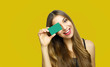 © zigres - Portrait of a pretty young woman holding credit card at her face isolated over yellow background