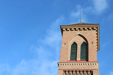 Old historic stone Catholic church steeple against bright blue skies