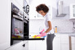 © Andrey Popov - Woman Cleaning Oven With Napkin
