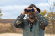 © Mountains Hunter - A hunter in a hat with binoculars looks out for prey