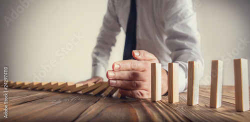 Fotomural Chain Reaction In Business Concept, Businessman Intervening Dominoes Toppling