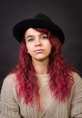 Emotional brunette in a hat and sweater with long hair posing in the Studio.