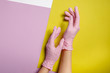 © Parilov - Latex gloves for beauty salon pink colors against background of yellow and white, top view, two hands dress