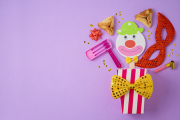 Jewish holiday Purim background with carnival mask, paper clown and hamantaschen cookies.