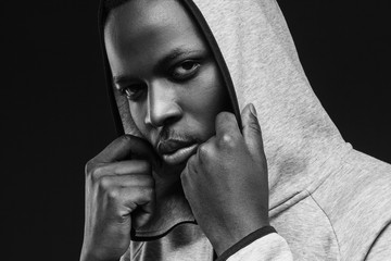 Portrait of bad guy with thug life, weating hoodie, looking at camera. African criminal concept