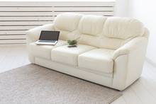 Business And Interior Concept - View Of A White Living Room With Sofa, An Open Laptop Computer, Home Interior