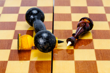 Dumbbell lies on a chessboard, two chess kings have fallen nearby. The victory of power over the mind.