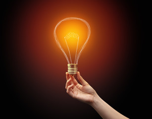 Hand holding light bulb on dark background. New idea concept