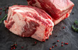 © Andrey - large raw pieces of pork ribs for BBQ on dark stone background, close-up