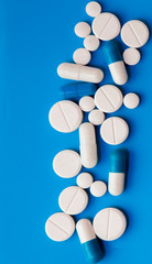 Scattered white pills on blue table. Mock up for special offers as advertising, web background or other ideas. Medical, pharmacy and healthcare concept. Copy space. Empty place for text or logo