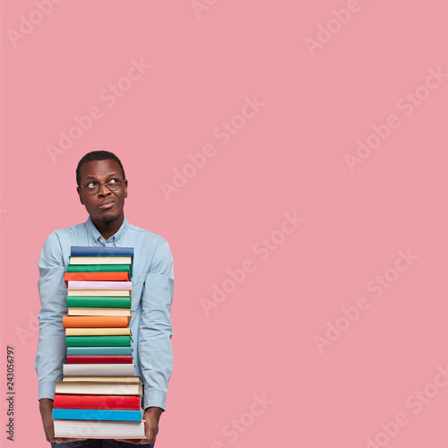 Fotografía Pensive dark skinned college student looks with indecisive hesitant thoughtful e