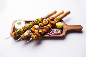 Wall Mural - Chicken Hariyali kakab or Malai malai kebab served with skewers and yogurt dip in a plate. selective focus