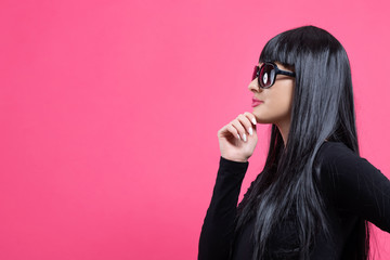 Wall Mural - Fashionable woman in sunglasses on a pink background