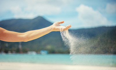 Wall Mural - Beach trip vacation tropics concept, white sand strewed from female hands