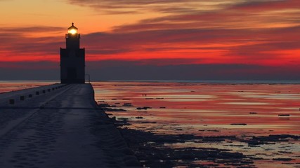 Wall Mural - Iconic Lighthouse stands alone in frozen Lake Michigan harbor, twilight time lapse.