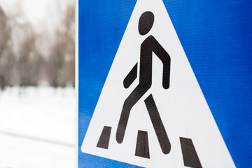 Road sign pedestrian. Pedestrian transit traffic sign. Pedestrian crossing, road sign. Blue metallic sign with a walking man drawn in a triangle