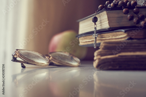 Fotografie, Obraz The rosary beads on Catholic Church liturgy books and old glasses and ripe apple on the side of them